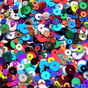 May include: A large assortment of colourful round sequins in various sizes. The sequins are made of shiny, metallic material and come in shades of blue, green, red, gold, silver, and purple.