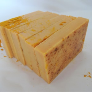 Puede incluir: Una pila de seis barras rectangulares de jab&oacute;n hecho a mano. El jab&oacute;n es de color amarillo claro con una textura moteada. El jab&oacute;n est&aacute; dispuesto en forma de pir&aacute;mide.