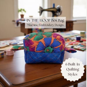 May include: A quilted box bag with a vibrant floral pattern in blue, orange, and purple. The bag has a blue quilted base and the text "IN-THE-HOOP Box Bag Machine Embroidery Design" is visible. The image also shows "6 Built-In Quilting Styles".