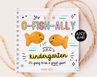 May include: A white card with a blue, yellow, pink, and green border. The card has a fish-shaped cracker on it and says "O-FISH-ALLY in kindergarten it's going to be a great year!" with a space for a name. The card also has a small circle with the text "ANY grade" in it.