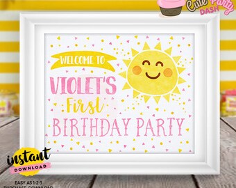 May include: Printable 8x10 inch welcome sign for a first birthday party. The sign features a yellow sun with a smiling face and the text "Welcome to Violet's First Birthday Party" in pink letters. The background is white with pink and yellow confetti.