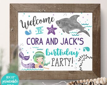 Op de afbeelding: Printbare welkomstbord van 20,3 x 25,4 cm voor een verjaardagsfeest. Het bord toont een zeemeermin, een haai en de tekst "Welkom bij Cora en Jack's Birthday Party!" in paars, turquoise en groen.