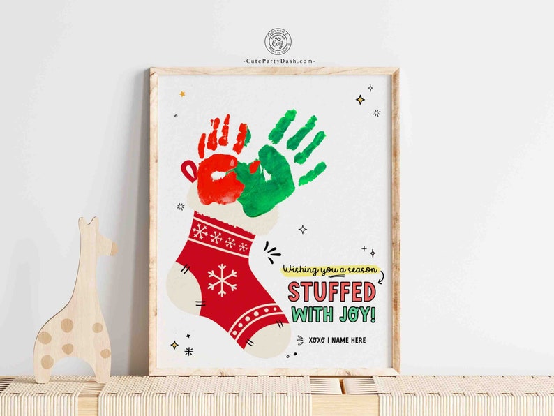 May include: A red and white Christmas stocking with green and red handprints inside. The stocking has a white cuff and a snowflake design. The text "Wishing you a season STUFFED WITH JOY! XOXO | NAME HERE" is written below the stocking.