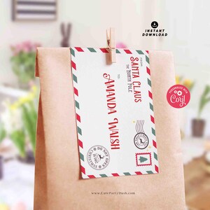 May include: A red and white envelope with green and white stripes, addressed to Amanda Walsh from Santa Claus at the North Pole. The envelope is attached to a brown paper bag with a clothespin.