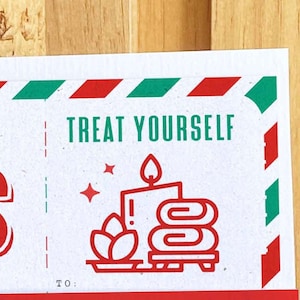 May include: A white card with red and green stripes at the top. The card says "TREAT YOURSELF" in green letters. There is a red and white illustration of a candle, a plant, and towels on a plate. The card also says "TO:" at the bottom.