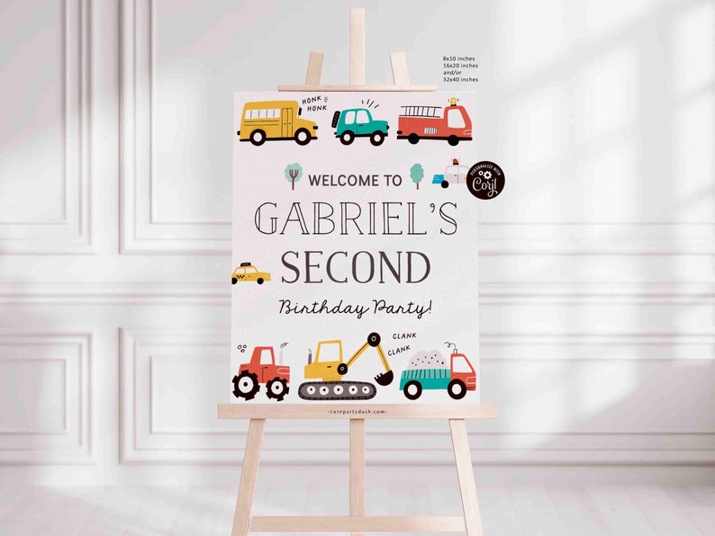 May include: A white welcome sign with a light pink background featuring a cartoon illustration of various vehicles, including a school bus, a car, a fire truck, a taxi, a tractor, a construction vehicle, and a dump truck. The sign reads "Welcome to Gabriel's Second Birthday Party!" with a small logo that says "So Coril".