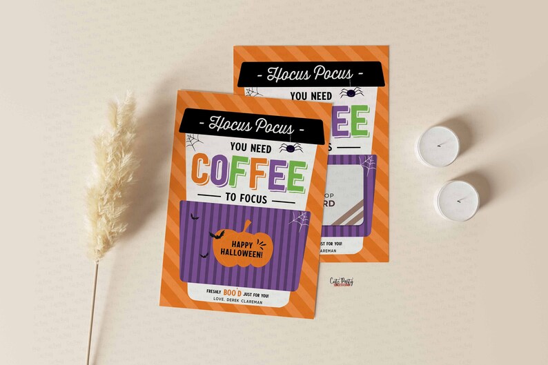May include: A Halloween-themed gift card holder with an orange and purple striped background. The holder features a coffee cup with the text "Hocus Pocus You Need Coffee To Focus" and a pumpkin with the text "Happy Halloween!"
