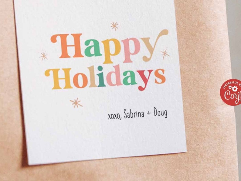 May include: A white card with the text "Happy Holidays" in colorful letters. The text "xoxo, Sabrina + Doug" is printed below the greeting.