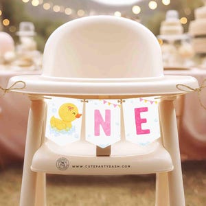 May include: A yellow rubber ducky with a pink bow sits on a white high chair with a pink and yellow banner that reads "ONE" and the text "www.cutepartydash.com".