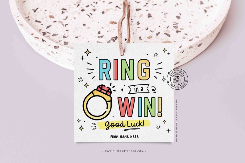 May include: A colorful printable tag with the text "RING in a WIN! Good Luck!" and a cartoon ring with a red gem. The tag is decorated with stars and plus signs.