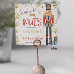 May include: A Christmas card featuring a watercolor illustration of a nutcracker holding a gift. The card reads "We would go nuts without you as our friend. Happy Holidays from the [Il] family."