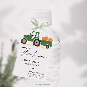 May include: A green tractor with a trailer full of orange pumpkins. The tractor is on a white tag with the text "Thank you for plowing on over! Your friend Atticus".