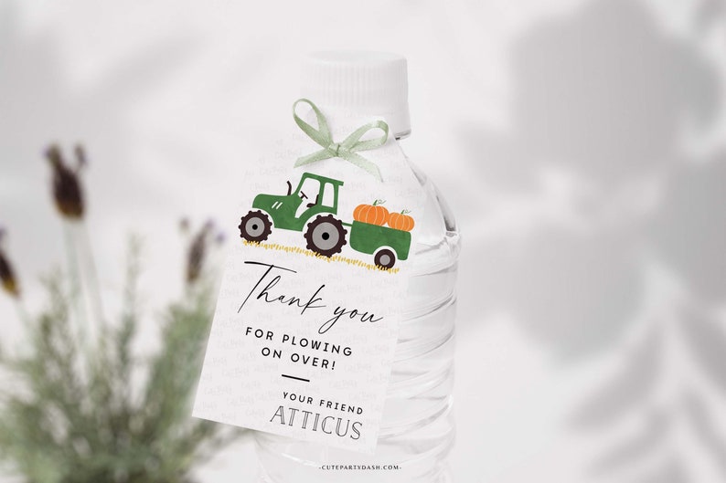 May include: A green tractor with a trailer full of orange pumpkins. The tractor is on a white tag with the text "Thank you for plowing on over! Your friend Atticus".