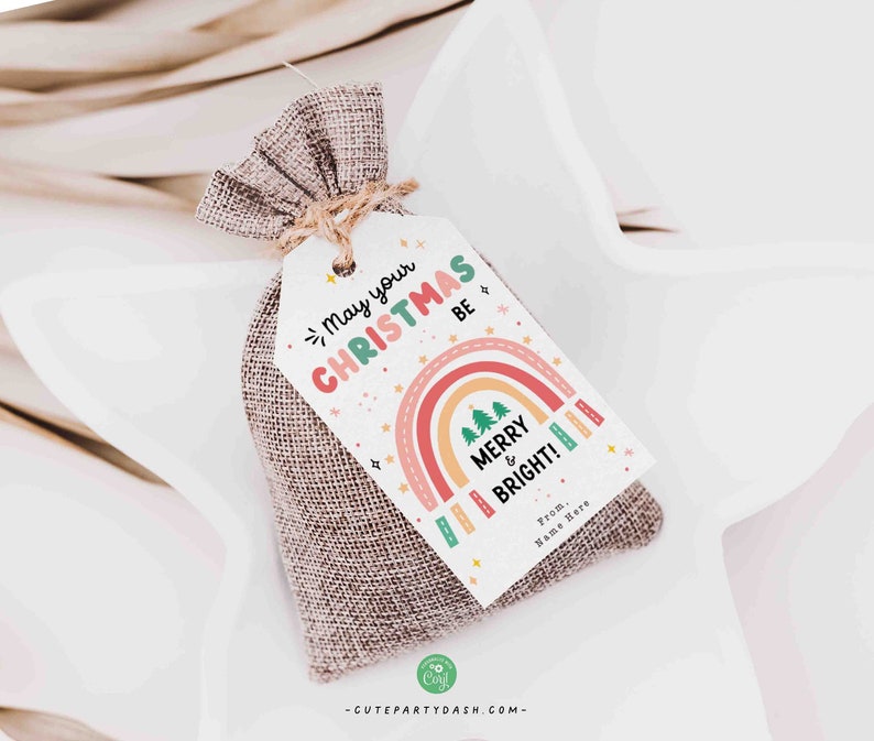 May include: A white gift tag with a rainbow design and the text "May your Christmas be Merry & Bright!"  The tag is tied to a small burlap bag.