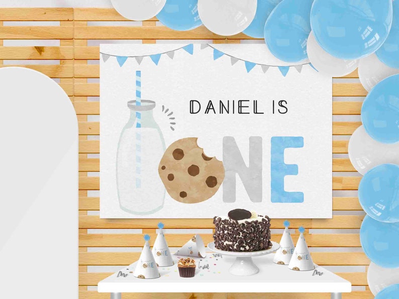 May include: A blue and gray 'One' banner with a cookie and milk illustration. The banner says 'Daniel is One'. There are blue and white balloons, a cake with chocolate frosting and sprinkles, and party hats with the word 'One' on them.
