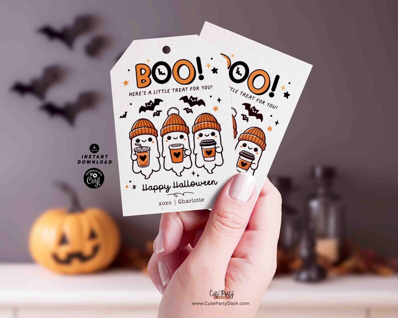 以下が含まれることがあります： オレンジ色の「BOO！」の文字が入った、白いハロウィーンのギフトタグ2枚。オレンジ色の帽子をかぶり、コーヒーカップを持ったお化けのイラストが描かれています。タグには「Here's a little treat for you!」と「Happy Halloween」と書かれています。