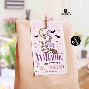 May include: A Halloween-themed gift bag with a light pink tag featuring a cartoon witch duck riding a broom. The tag reads "Witching you a happy Halloween!" with bats, stars, and a crescent moon. The bag is brown.