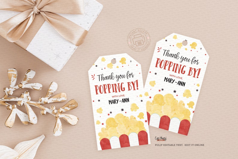 May include: Two popcorn-themed gift tags with the text "Thank you for POPPING BY!" in red and black. The tags feature a popcorn graphic and are decorated with stars. A gift box and decorative gold branch are in the background.