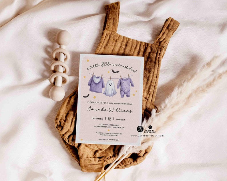 Pu&ograve; includere: Un invito per un baby shower con il testo "a little boo is almost due!" presenta illustrazioni di vestiti per bambini e un fantasma. L'invito &egrave; su sfondo rosa, con una tutina marrone e un sonaglio di legno.