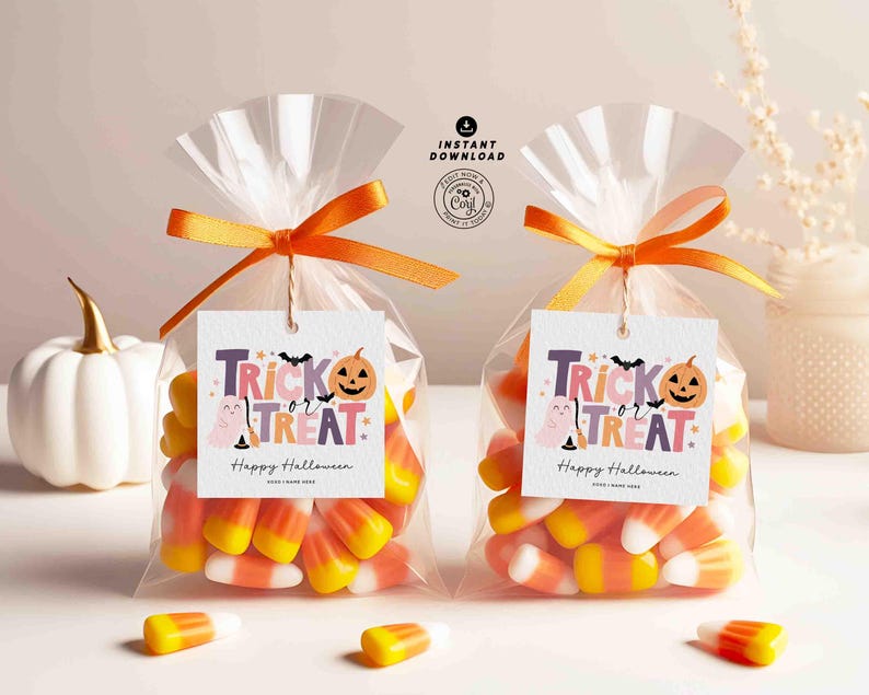 Peut inclure: Deux sacs transparents remplis de bonbons en forme d'&eacute;pi de ma&iuml;s, attach&eacute;s avec des rubans orange et &eacute;tiquet&eacute;s avec des &eacute;tiquettes "Trick or Treat". Une citrouille blanche avec une tige dor&eacute;e est &agrave; gauche. Les &eacute;tiquettes ont une chauve-souris et une citrouille.