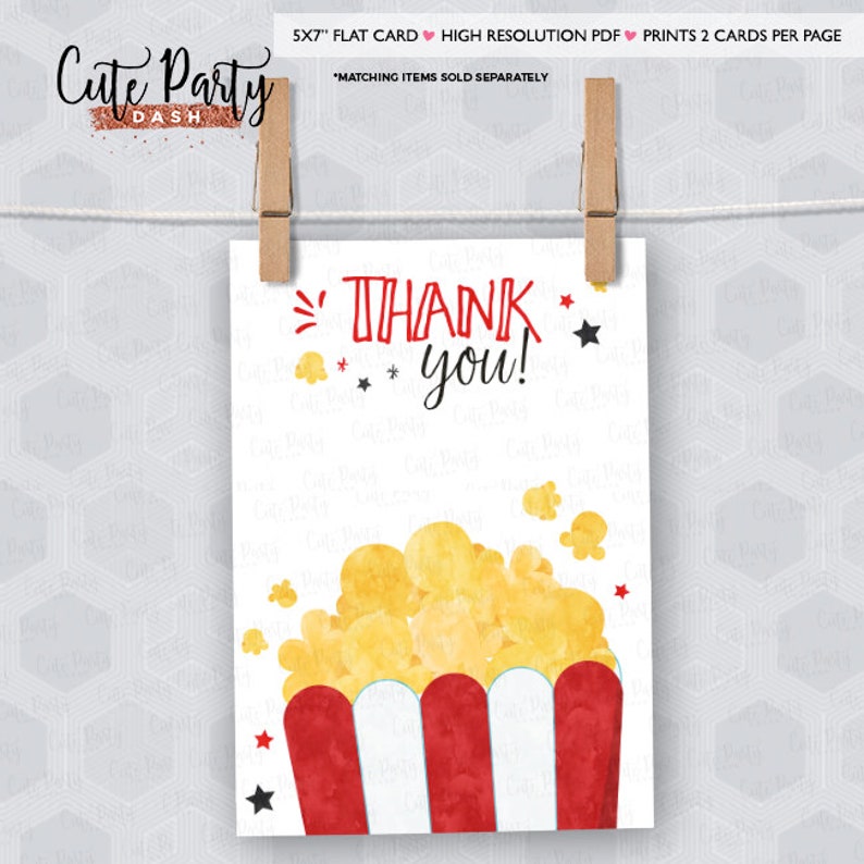 May include: A white flat card with a popcorn design. The card features a red and white popcorn container with yellow popcorn. The words "Thank You!" are written in red and black. The card is held by two wooden clothespins.
