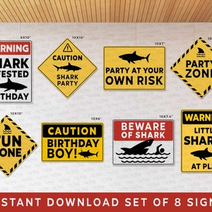 Puede incluir: Conjunto de ocho carteles de fiesta imprimibles con tem&aacute;tica de tiburones en amarillo y negro con texto de advertencia y precauci&oacute;n. Los carteles son de varios tama&ntilde;os y presentan diferentes frases relacionadas con los tiburones como "Cumplea&ntilde;os infestado de tiburones", "Zona de fiesta", "Zona de diversi&oacute;n" y "Peque&ntilde;os tiburones en juego".