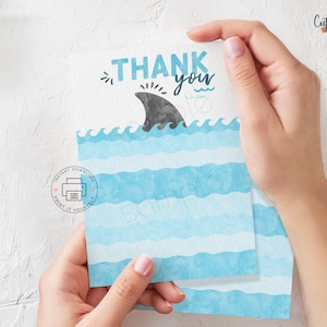 May include: Thank you card with a blue and white watercolour design. The card features a shark fin and the text "Thank you".
