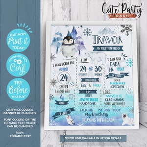 May include: A blue and white first birthday sign with a penguin and polar bear illustration. The sign says "Travor My First Birthday" and includes details like age, weight, height, and favorite foods.