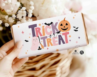 May include: A white candy bar wrapper with the words "Trick or Treat" in purple, orange, and pink. The design includes a smiling jack-o'-lantern, bats, stars, and a ghost with a witch's broom. The wrapper is held by a person.