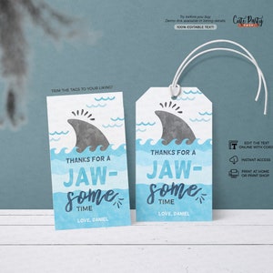 May include: Two blue and white favour tags with a shark fin graphic and the text "Thanks for a Jaw-some Time" with the name "Love, Daniel" at the bottom.