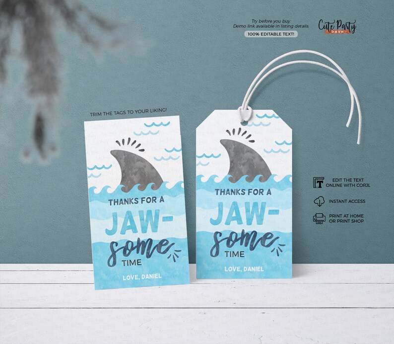 May include: Two blue and white favour tags with a shark fin graphic and the text "Thanks for a Jaw-some Time" with the name "Love, Daniel" at the bottom.