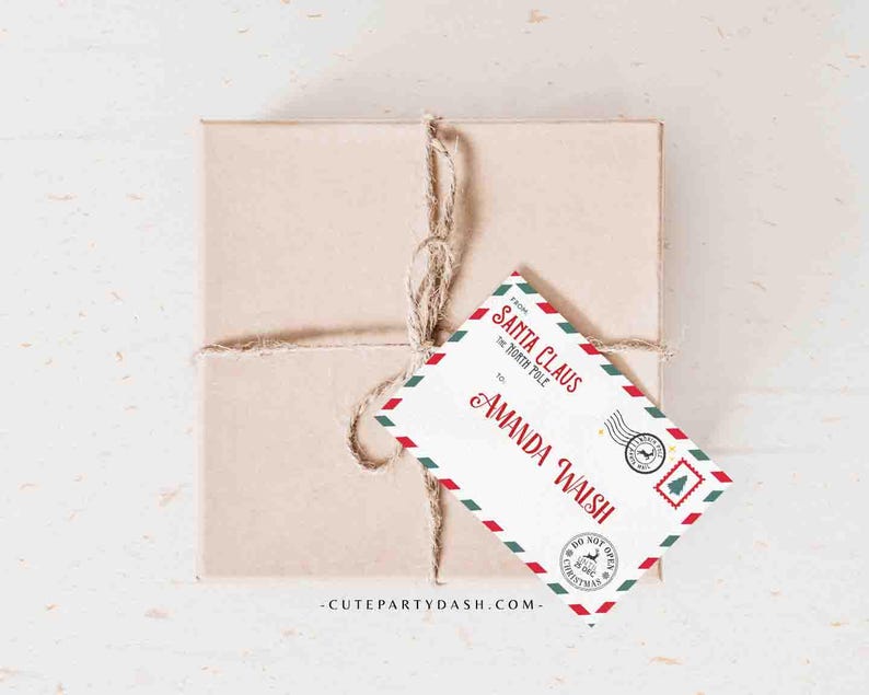 May include: A red and green Christmas gift tag with a white background. The tag is shaped like an envelope and has the text "Santa Claus, The North Pole" and "Amanda Walsh" on it. The tag also has a red and green stamp that says "Do Not Open Until Christmas".