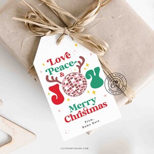 May include: A white gift tag with a red, green and pink design. The tag features the text "Love Peace & Joy" with a disco ball and reindeer antlers. The text "Merry Christmas" is below the design, followed by "From, Name Here".