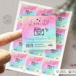 Op de afbeelding: Een set van 10 printbare fotohok-rekwisieten met een regenboog-ombre-achtergrond met een zwart-witte camera-afbeelding en de tekst "Love it? Snap it & share it". De rekwisieten bevatten ook sociale media-pictogrammen en de tekst "@yourshop #yourhashtag".
