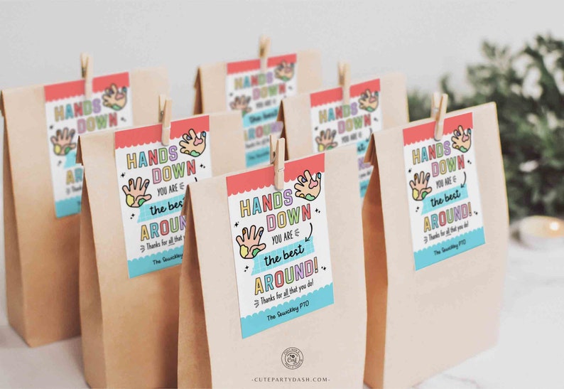 K&ouml;nnte beinhalten: Ein Satz brauner Papiert&uuml;ten mit bunten Geschenkanh&auml;ngern, auf denen "Hands Down You Are The Best Around!" steht. Die Anh&auml;nger haben ein Handabdruckdesign mit bunten Farbflecken. Der Text "The Sawicki PTO" befindet sich am unteren Rand der Anh&auml;nger.
