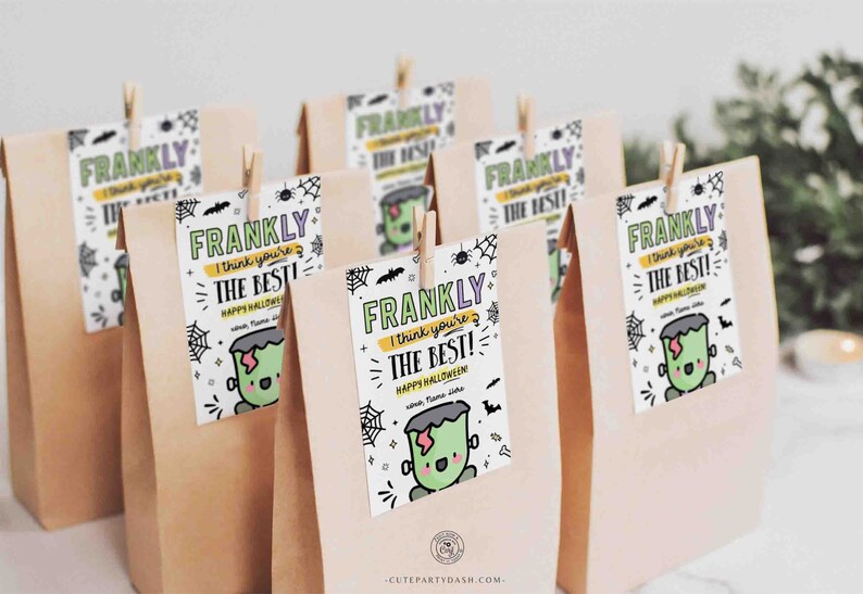 Op de afbeelding: Een set bruine papieren zakken met kleurrijke labels eraan bevestigd. De labels tonen een cartoon Frankenstein-monster en de tekst "FRANKLY I think you're THE BEST! HAPPY HALLOWEEN".