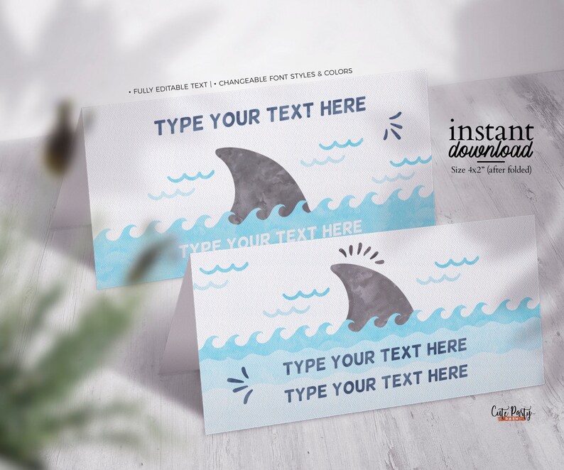 May include: Editable printable place cards featuring a shark fin and blue watercolour waves. The text "Type your text here" is displayed on the cards. The cards are 4x2 inches when folded.