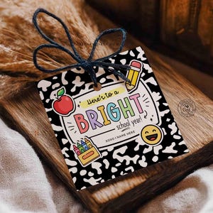 Op de afbeelding: Een cadeaulabel met een zwart-witte dalmati&euml;rprint achtergrond. Het label bevat de tekst "Here's to a BRIGHT school year!" met kleurrijke letters en schoolthema-illustraties, waaronder een appel, potlood, kleurpotloden en een smiley.