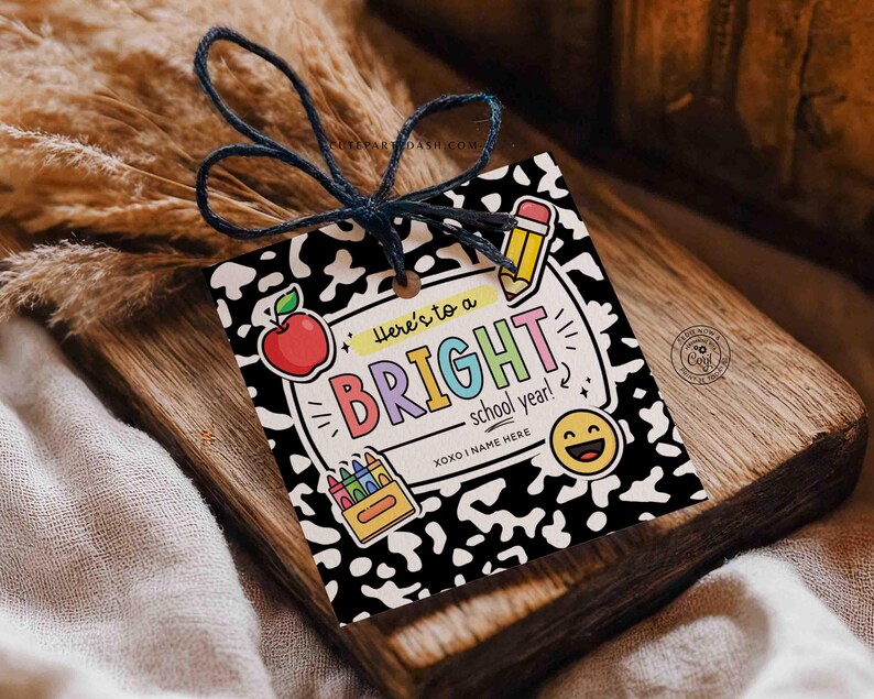 Op de afbeelding: Een cadeaulabel met een zwart-witte dalmati&euml;rprint achtergrond. Het label bevat de tekst "Here's to a BRIGHT school year!" met kleurrijke letters en schoolthema-illustraties, waaronder een appel, potlood, kleurpotloden en een smiley.