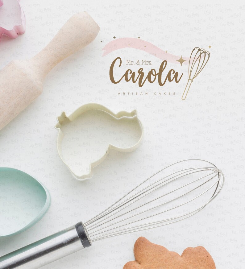 Puede incluir: Una vista cenital de utensilios de reposter&iacute;a y un logotipo. Se ven un rodillo de madera, un cortador de galletas ovalado azul claro y un batidor de metal. El logotipo dice "Mr. & Mrs. Carola ARTISAN CAKES" con una ilustraci&oacute;n de batidor.