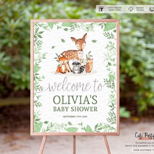 May include: A printable welcome sign for a baby shower with a woodland theme. The sign features a deer, fox, raccoon, and owl surrounded by green leaves. The text on the sign reads "Welcome to Olivia's Baby Shower September 19th, 2020".