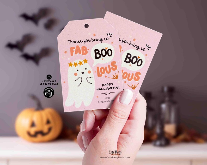 May include: Pink Halloween gift tags with a ghost illustration and the words "FAB BOO LOUS". The tags also say "Happy Halloween!" and include the text "Thanks for being so". The tags are held by a person.