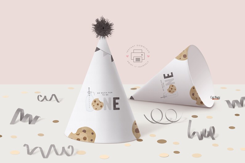 May include: Printable party hat featuring a cookie design and the text "So much fun to be one". The hat is white with brown and black cookie illustrations. The hat is lying on a white surface with confetti.