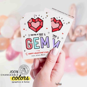 K&ouml;nnte beinhalten: Zwei wei&szlig;e Valentinstags-Geschenkanh&auml;nger mit einem roten Edelstein-Herz-Design und den Worten "YOU'RE A TRUE GEM". Die Anh&auml;nger enthalten auch den Text "HAPPY VALENTINE'S DAY" und "xoxo, Alison Walsh".