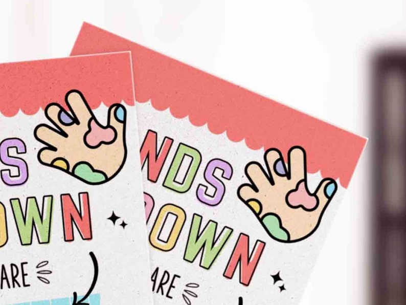 K&ouml;nnte beinhalten: Zwei bunte Schilder mit dem Text "Hands Down" und einer Comic-Hand mit Farbe darauf. Die Schilder sind rosa und wei&szlig; mit einem gewellten Rand.