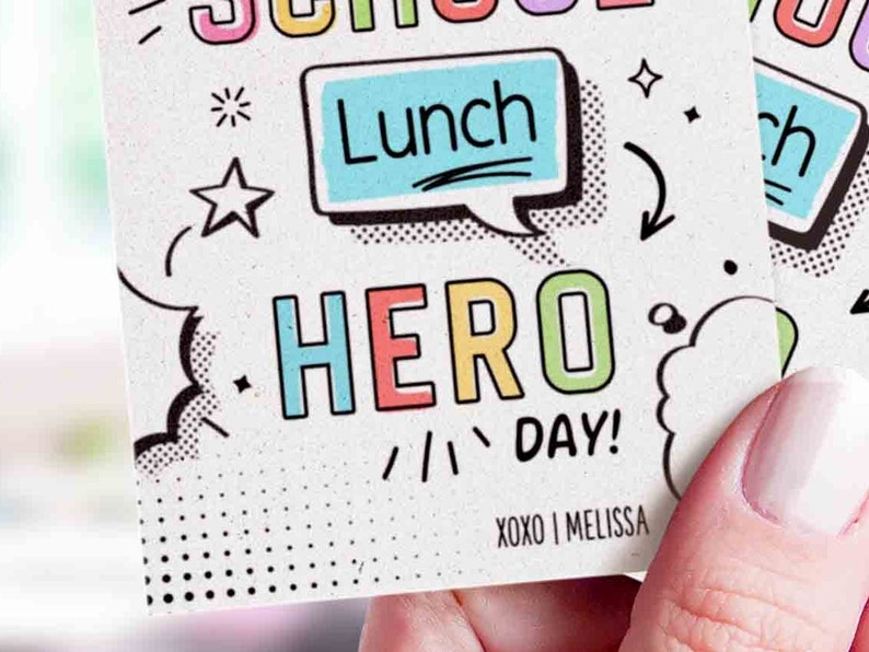 May include: A colorful card with the words "School Lunch Hero Day!" in a comic book style font. The card has a speech bubble with the word "Lunch" inside. The card is signed "XOXO Melissa".