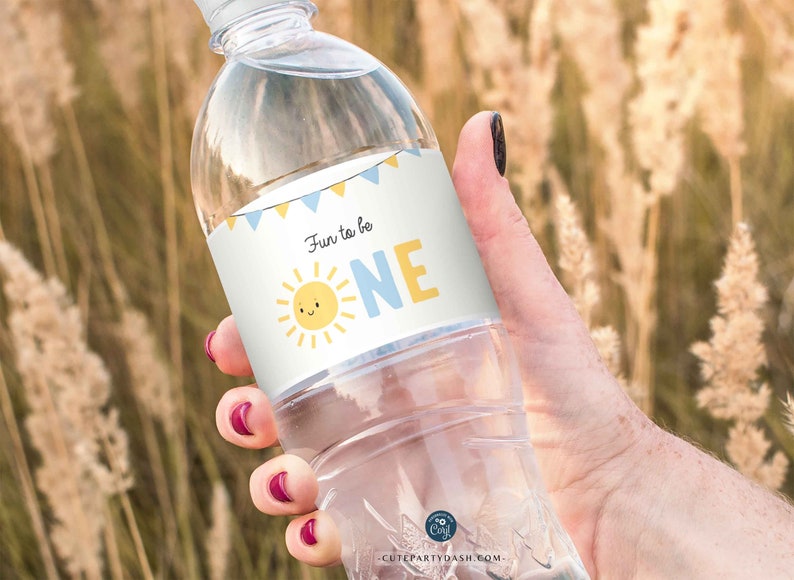 Puede incluir: Etiqueta de botella de agua con un dise&ntilde;o de sol azul y amarillo y el texto "Fun to be ONE".