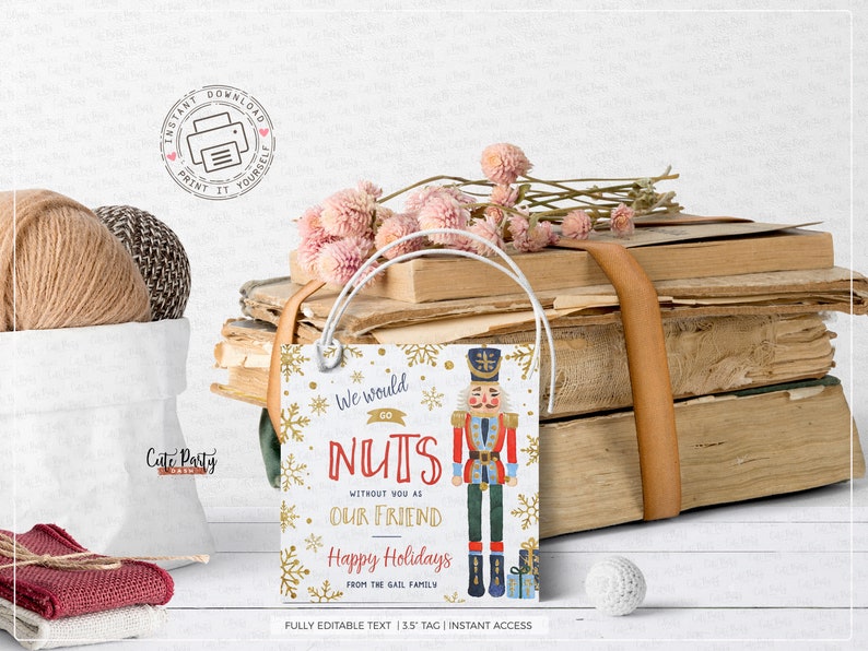 May include: A white gift tag with gold snowflakes and a red and blue illustration of a nutcracker. The text on the tag reads "We would go NUTS without you as our friend Happy Holidays from the Gail family".