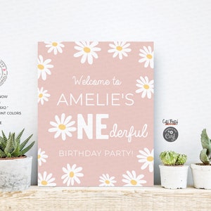 May include: A pink printable sign with white daisies and the text "Welcome to Amelie's One-derful Birthday Party!"