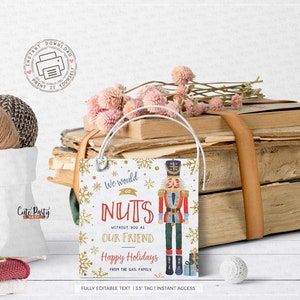 May include: A white gift tag with gold snowflakes and a red and blue illustration of a nutcracker. The text on the tag reads "We would go NUTS without you as our friend Happy Holidays from the Gail family".